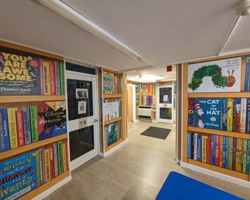 Colourful reading themed wall art for a school library highlighting popular books and book spines. Designed and installed by Design for Education.