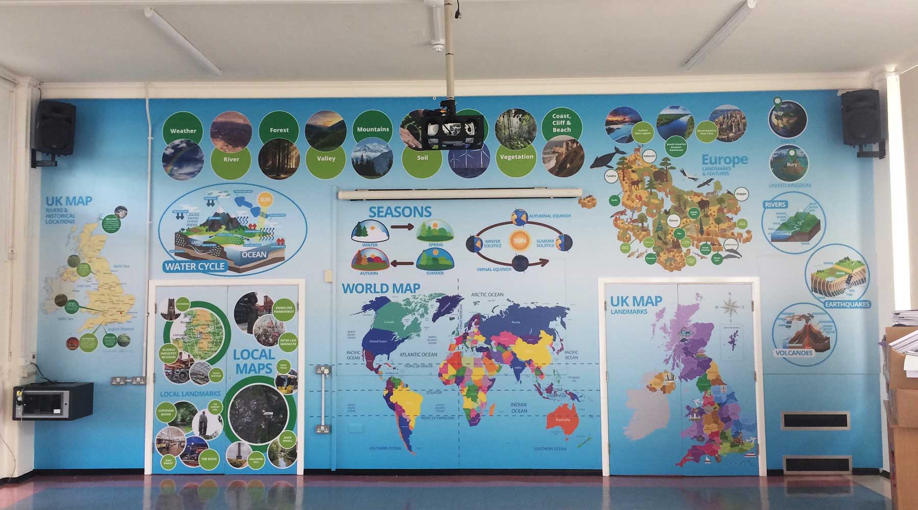 Bespoke primary school geography wall art featuring world and local maps in the school hall at East Ward Community Primary School.